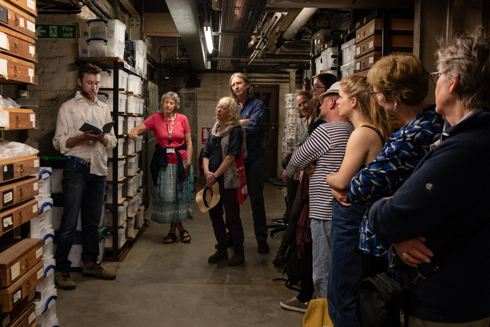 A group of people attending a reading from 'The Mapping of Jan Mayen' in the Univeristy of Bristol geological stores.